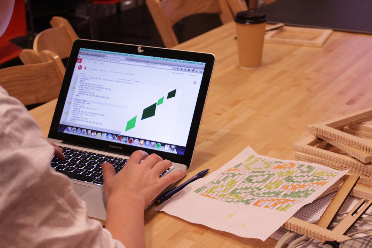 Photo of one of the attendees coding on their computer. They are programming a drawn pattern they designed, which is by their right side.