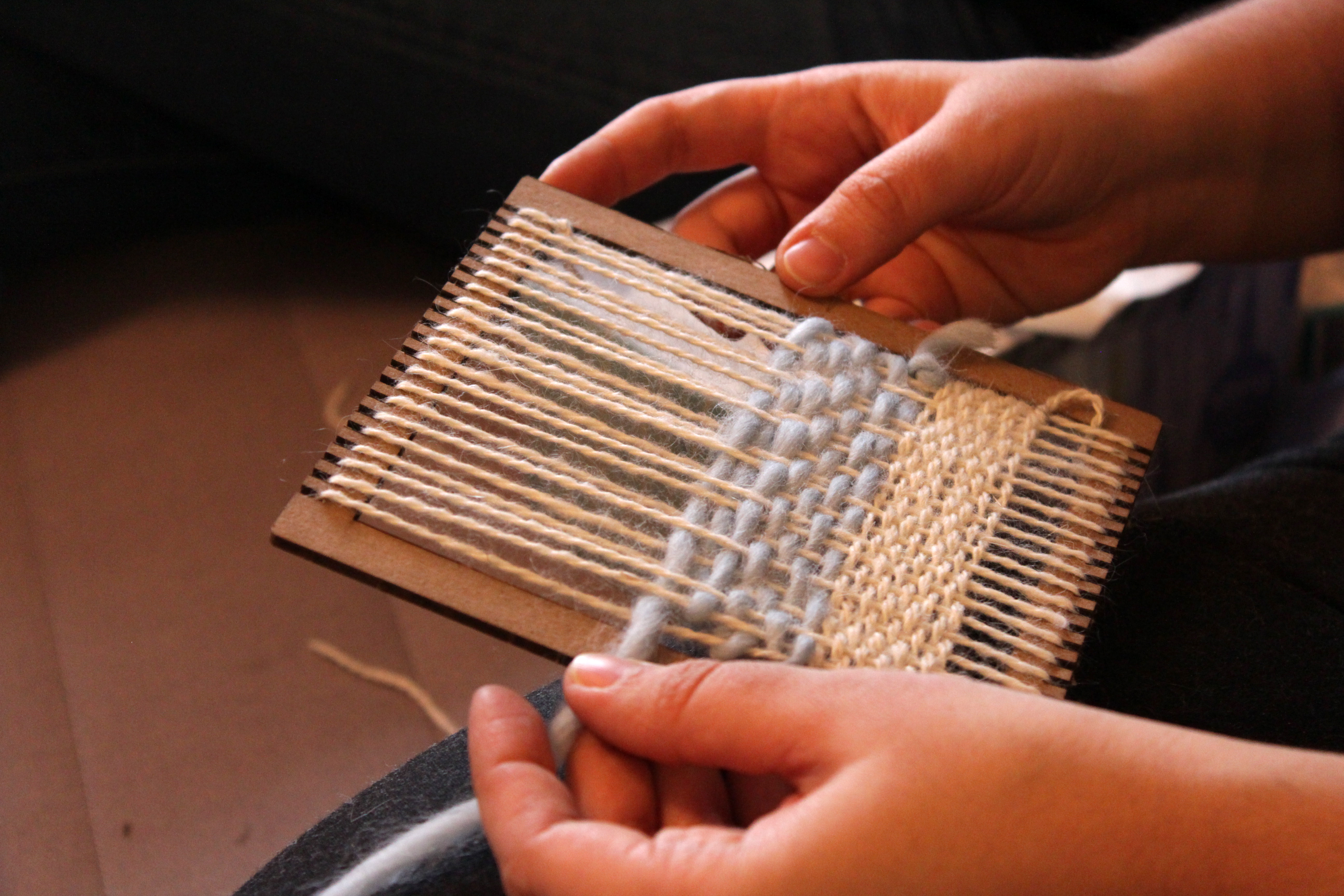 Photo of one participants weaving on a small frame loom.